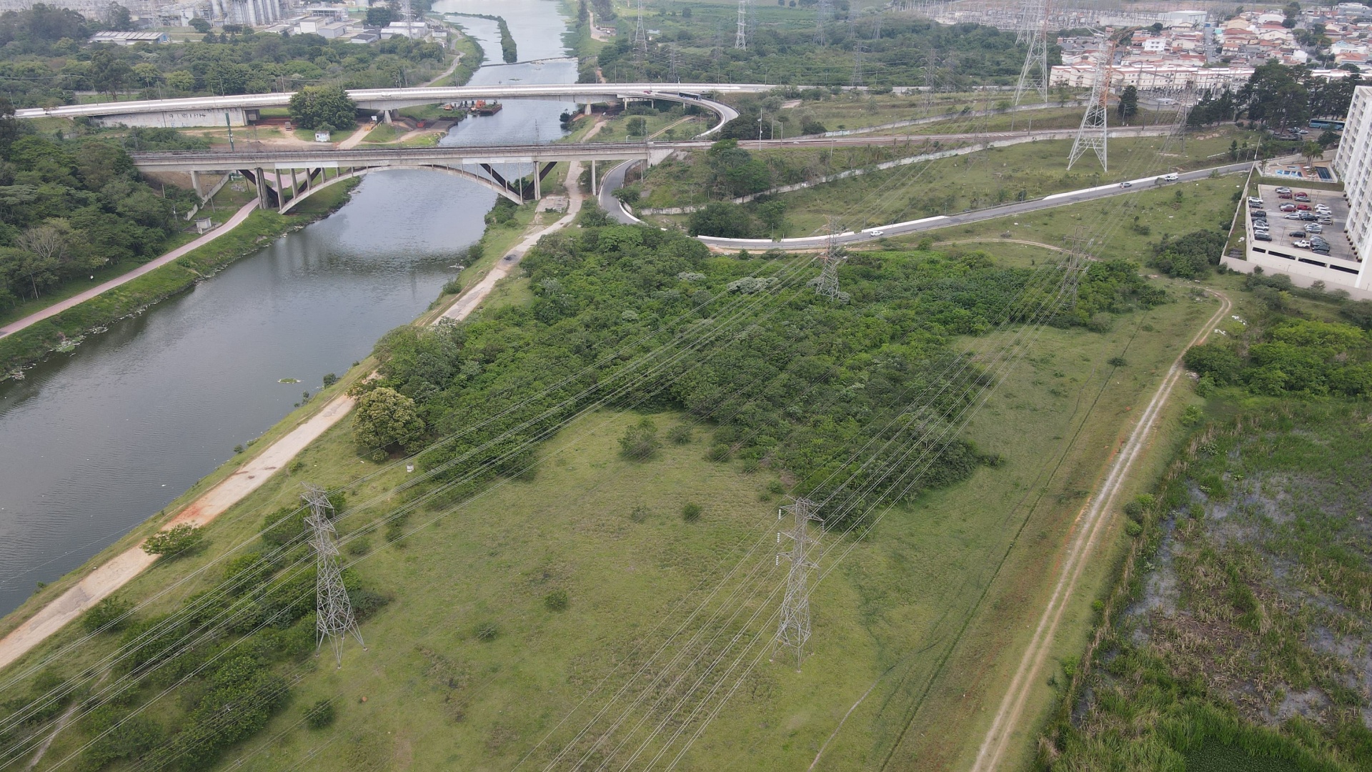 Vista aérea de ponte sobre o rio com vegetação marginal e linhas de transmissão